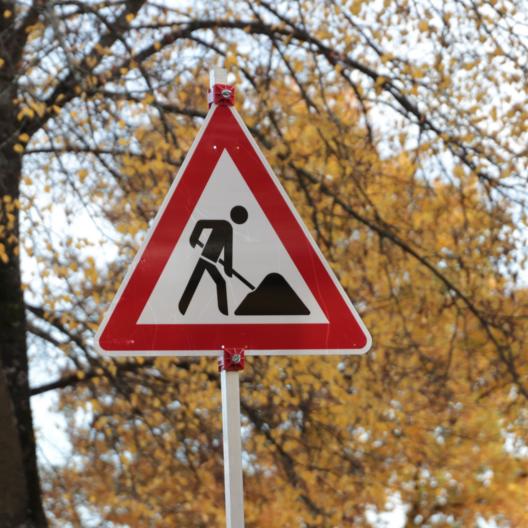Verkehrsschild Baustelle vor herbstlichen Bäumen